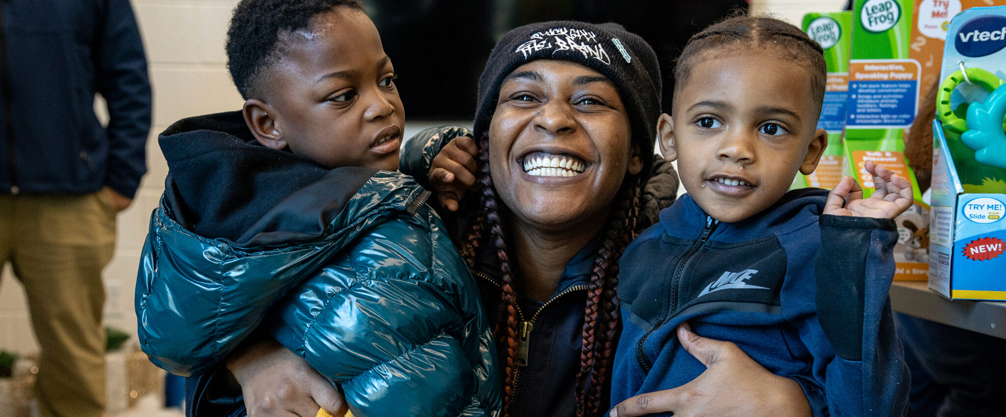 Woman at Life Deeds event smiling holding two toddlers